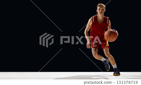 Basketball player in red uniform dribbling with sharp concentration Basketball player in red uniform dribbling with sharp concentration 131378719
