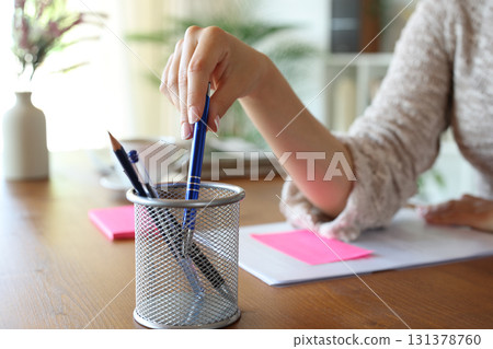 Woman hand taking pen from pencil cup Woman hand taking pen from pencil cup 131378760