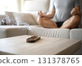 Man doing yoga with incense stick burning in foreground at home 131378765