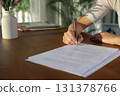 Woman hand signing document on wooden table at sunset 131378766