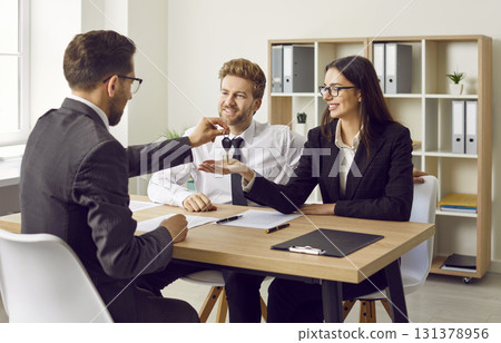 Real estate agent gives keys to new house or apartment to happy young family couple 131378956