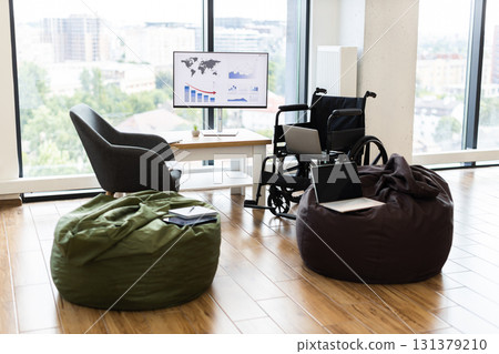 Innovative office setting with wheelchair accessibility, comfortable bean bags, and technology tools placed in front of large window with city view Innovative office setting with wheelchair accessibility, comfortable bean bags, and technology tools placed in front of large window with city view 131379210