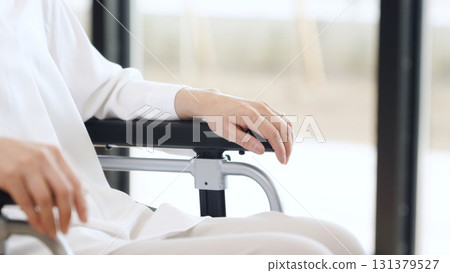 A caregiver placing his hand on an elderly person in a wheelchair 131379527
