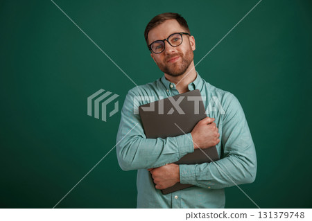 Silver colored laptop in hands. Man is standing against background in the studio 131379748