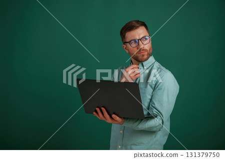 Silver colored laptop in hands. Man is standing against background in the studio Silver colored laptop in hands. Man is standing against background in the studio 131379750