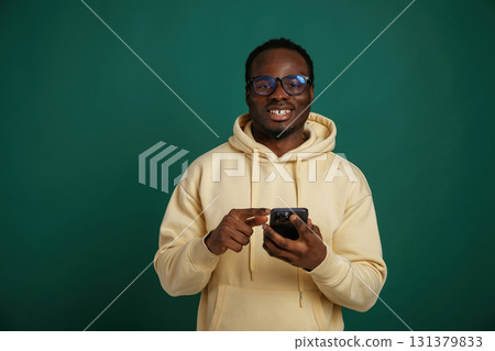 Using smartphone. African American man is standing against green background in the studio Using smartphone. African American man is standing against green background in the studio 131379833