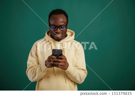 Using smartphone. African American man is standing against green background in the studio Using smartphone. African American man is standing against green background in the studio 131379835