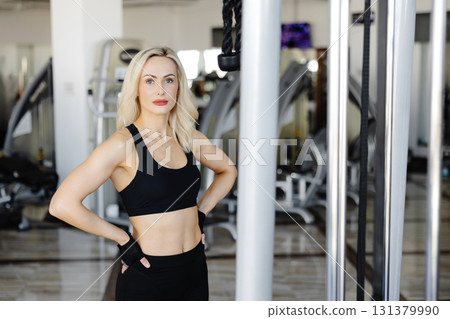 Athletic woman wearing black sportswear posing in a gym Athletic woman wearing black sportswear posing in a gym 131379990