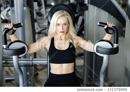 Determined sportswoman exercising using gym equipment for chest muscles 131379999