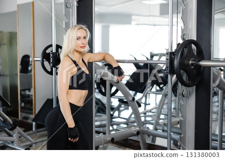Athletic woman resting after exercising with weights in modern gym 131380003