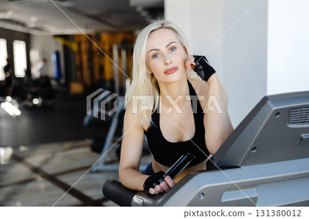 Determined sportswoman running on treadmill during fitness workout in gym Determined sportswoman running on treadmill during fitness workout in gym 131380012