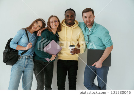 Smiling, looking forward. Group of young people are standing against white background Smiling, looking forward. Group of young people are standing against white background 131380046
