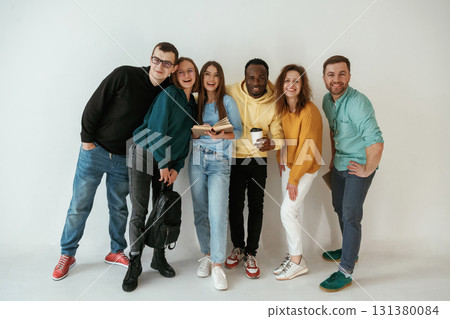 Positive friends. Group of young people are standing against white background Positive friends. Group of young people are standing against white background 131380084