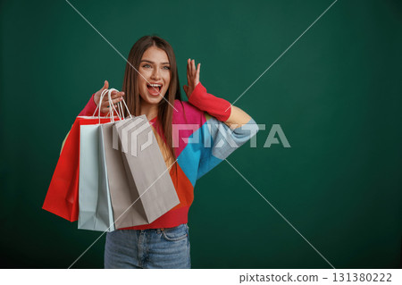 Crazy sale, shocked face, with shopping bags. Young woman is standing against green background in the studio Crazy sale, shocked face, with shopping bags. Young woman is standing against green background in the studio 131380222