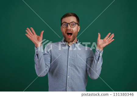 Shocked facial expression. Man is standing against background in the studio 131380346