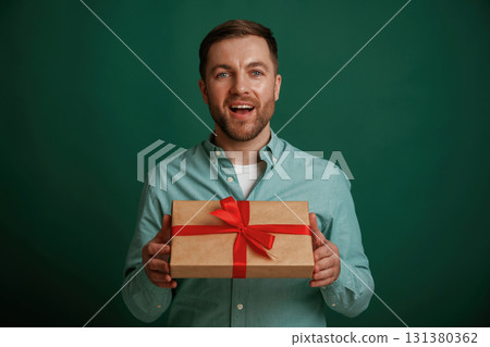 Little gift box in hands. Man is standing against background in the studio 131380362
