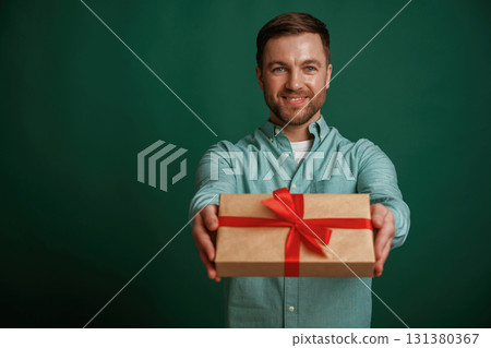 Conception of holidays, with gift box. Man is standing against background in the studio Conception of holidays, with gift box. Man is standing against background in the studio 131380367