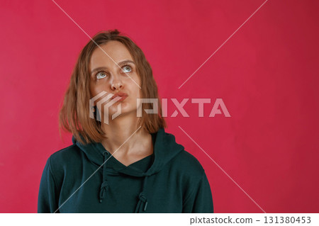 Making funny faces. Young woman is standing against red background in the studio 131380453
