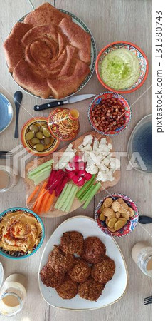 Colorful vegetarian potluck dinner with hummus, falafel, pie, and fresh vegetables, flatlay mobile photo. Concept of food, cuisine, meal, authenticity. Colorful vegetarian potluck dinner with hummus, falafel, pie, and fresh vegetables, flatlay mobile photo. Concept of food, cuisine, meal, authenticity. 131380743