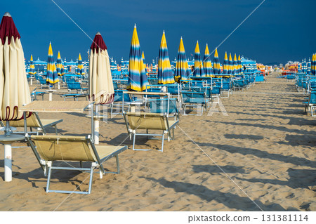 Sun loungers on sandy beach with Umbrellas. Empty seaside resort. Italy. 131381114