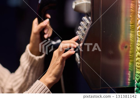 A Person Using a Payphone at Night in an Urban Setting, Highlighting Nostalgic Communication A Person Using a Payphone at Night in an Urban Setting, Highlighting Nostalgic Communication 131381142