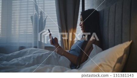 Young Woman in Bed Browses Content on Social Media Young Woman in Bed Browses Content on Social Media 131381143