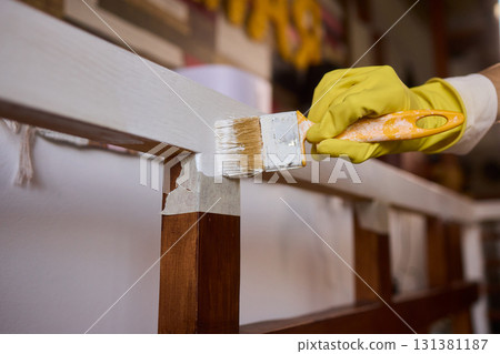 Engage in DIY chair restoration using a paint brush and protective gloves for the process Engage in DIY chair restoration using a paint brush and protective gloves for the process 131381187