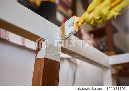 Engage in DIY chair restoration using a paint brush and protective gloves for the process Engage in DIY chair restoration using a paint brush and protective gloves for the process 131381192
