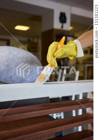 Engage in DIY chair restoration using a paint brush and protective gloves for the process Engage in DIY chair restoration using a paint brush and protective gloves for the process 131381223
