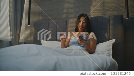 Girl Sits in Bed Eating Nuts for Breakfast and Chatting on Messenger Girl Sits in Bed Eating Nuts for Breakfast and Chatting on Messenger 131381245