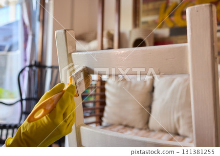 Engage in DIY chair restoration using a paint brush and protective gloves for the process Engage in DIY chair restoration using a paint brush and protective gloves for the process 131381255