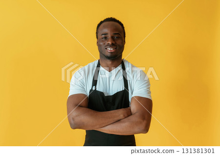 Cafe worker. Black man is in the studio against yellow background Cafe worker. Black man is in the studio against yellow background 131381301