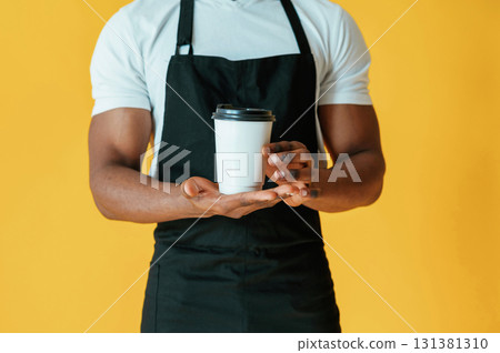 Cafe worker. Black man is in the studio against yellow background 131381310