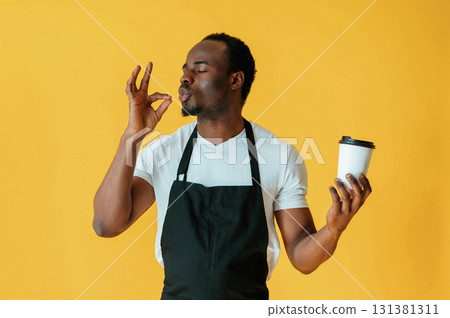 Cafe worker. Black man is in the studio against yellow background 131381311