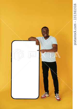 Cafe worker. Black man is in the studio against yellow background Cafe worker. Black man is in the studio against yellow background 131381316