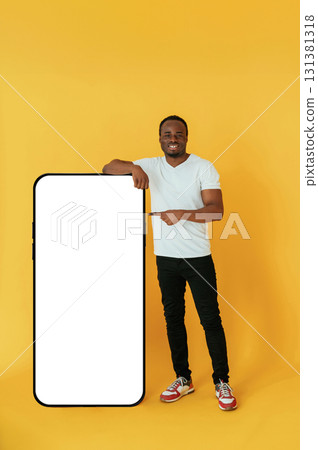 Cafe worker. Black man is in the studio against yellow background Cafe worker. Black man is in the studio against yellow background 131381318