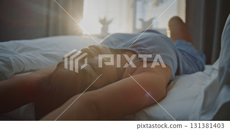 Young Woman in Blue Pajamas Basking in Bright Sunlight, Running Hands Through Hair 131381403