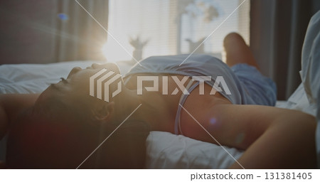 Young Woman in Blue Pajamas Basking in Bright Sunlight, Running Hands Through Hair Young Woman in Blue Pajamas Basking in Bright Sunlight, Running Hands Through Hair 131381405