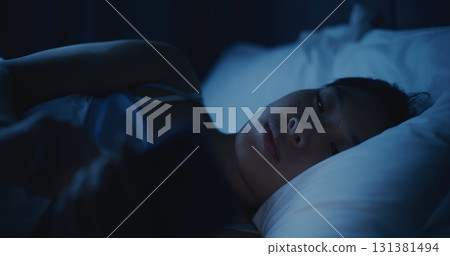 Portrait of Thoughtful Woman Lying Under Blanket, Staring Phone 131381494