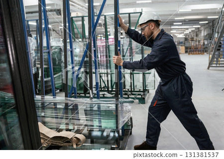 Moving the parts of windows. Factory worker is indoors with hard hat Moving the parts of windows. Factory worker is indoors with hard hat 131381537