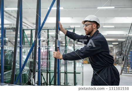 Moving the parts of windows. Factory worker is indoors with hard hat Moving the parts of windows. Factory worker is indoors with hard hat 131381538