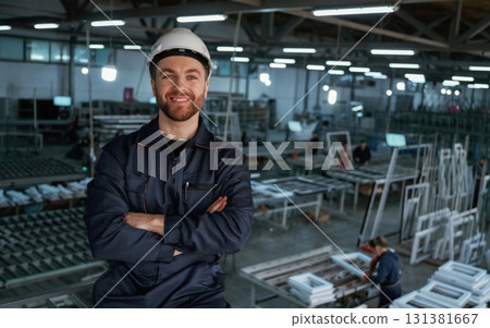 Handsome friendly guy. Factory worker is indoors with hard hat Handsome friendly guy. Factory worker is indoors with hard hat 131381667