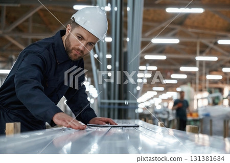 Checking quality of material, control. Factory worker is indoors with hard hat Checking quality of material, control. Factory worker is indoors with hard hat 131381684