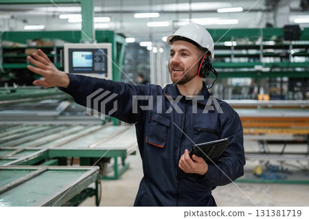 Giving orders by hand. Factory worker is indoors with hard hat 131381719