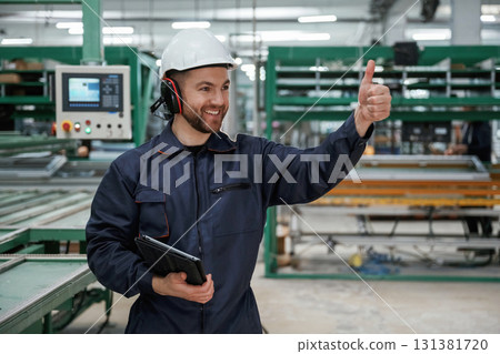 Giving orders by hand. Factory worker is indoors with hard hat Giving orders by hand. Factory worker is indoors with hard hat 131381720