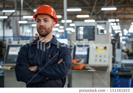 Confident facial expression. Factory worker is indoors with hard hat Confident facial expression. Factory worker is indoors with hard hat 131381855