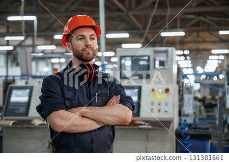 Confident facial expression. Factory worker is indoors with hard hat Confident facial expression. Factory worker is indoors with hard hat 131381861