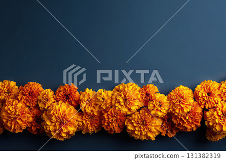 Horizontal banner with a garland of orange marigolds and space for your text on a blue background. Horizontal banner with a garland of orange marigolds and space for your text on a blue background. 131382319