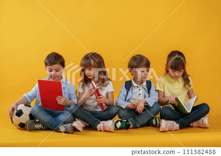 Sitting on the floor. Kids are together against yellow background 131382488