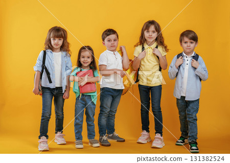 Standing and posing. Kids are together against yellow background 131382524